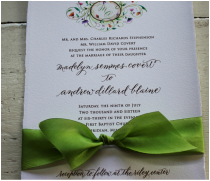 Custom invitation with green ribbon tied around the invite.